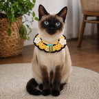 Cat wearing yellow knit pet collar with bee charm and white flowers