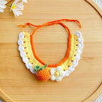 Flat-lay of artisan orange fruit knit pet collar on wooden tray